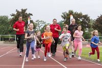 Danny Ecker (li.) und Kanu-Olympiasieger Andreas Dittmer (beide in roten Shirts) trainieren mit Kindern für das Deutsche Sportabzeichen. Foto: Meike Engels/ wirkhaus.